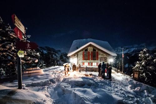 Alcune persone in inverno fuori dal Rifugio Zoia a Campo Moro in Valtellina