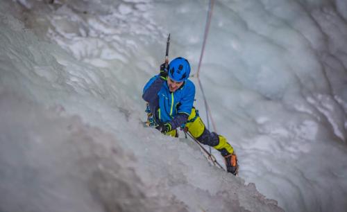 Un ragazzo sta facendo ice climbing su una parete rocchiosa ghiacciata in inverno in Valtellina