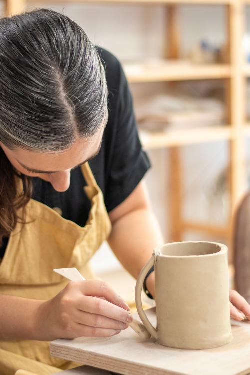 Una signora mentre rifinisce una tazza in ceramica realizzata durante un workshop a Milano in Lombardia