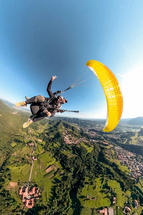 In volo con un parapendio biposto sullo sfondo le montagne bergamasche