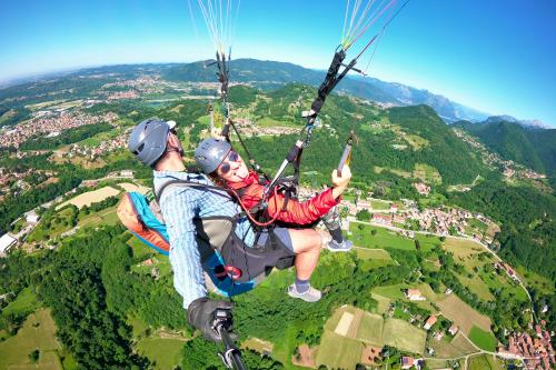 Una ragazza fa la linguaccia mentre insieme ad un pilota professionista sta volando su un parapendio biposto vicino a Bergamo